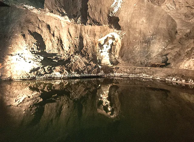 A figure carved in salt reflected in the still water of an underground lake